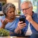 Older Black wife and white husband on couch concerned about suspicious Medicare phone call and requests for personal information