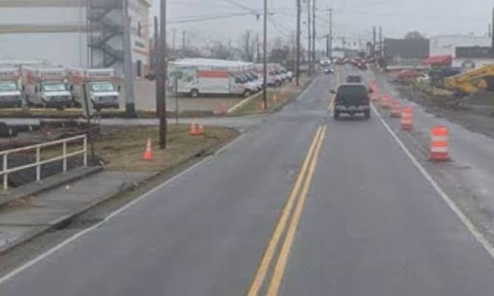 Illustration of traffic moving past construction barrels at a suburban intersection